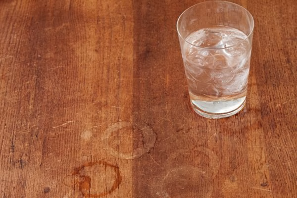 Circular water marks and moisture damage on a natural wood surface