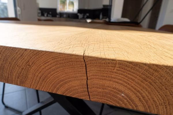 Close-up view of a crack on the edge of a thick oak wood table
